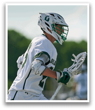 A man wearing a white and green jersey is holding a lacrosse stick. Description generated by AI
