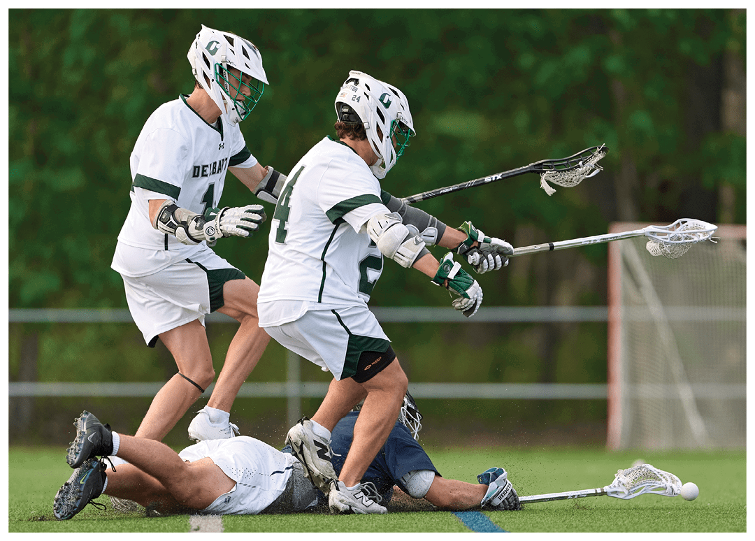 Two men playing lacrosse. Description generated by AI