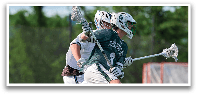 A man in a green shirt and white shorts is running with a lacrosse stick. Description generated by AI