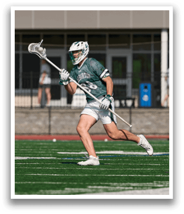 A man running on a field with a lacrosse stick. Description generated by AI