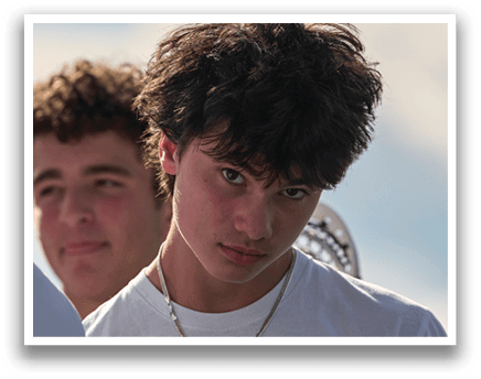 A boy with a white shirt and a necklace. Description generated by AI