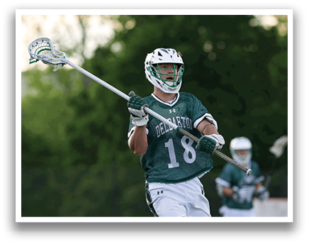 A man wearing a green and white jersey holding a lacrosse stick. Description generated by AI
