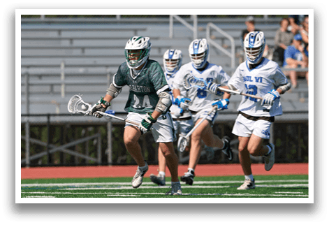 A man in a green and white uniform is running with a lacrosse stick. Description generated by AI