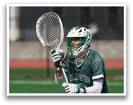 A person wearing a green and white shirt and holding a lacrosse net. Description generated by AI
