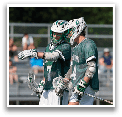 Two men wearing green jerseys and white shorts are standing on a field. Description generated by AI