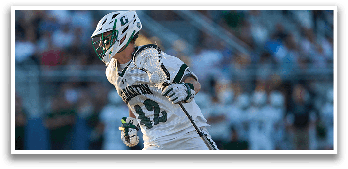 A man wearing a green and white jersey is running on a field. Description generated by AI