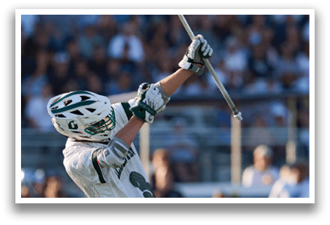 A man in a green and white uniform is running with a lacrosse stick. Description generated by AI