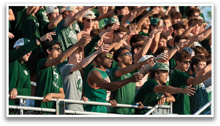 A group of men wearing green jerseys and white shorts are standing on a field. Description generated by AI