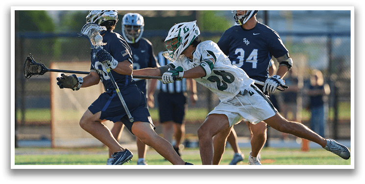 A man wearing a green and white shirt holding a lacrosse stick. Description generated by AI