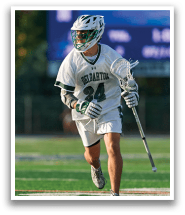 A man wearing a green shirt and white shorts is playing lacrosse. Description generated by AI