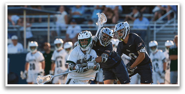Two men playing lacrosse on a field. Description generated by AI