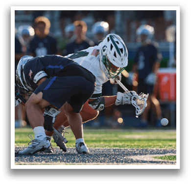 A man wearing a green and white jersey holding a lacrosse stick. Description generated by AI