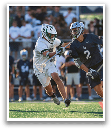 A man wearing a green and white uniform holding a lacrosse stick. Description generated by AI
