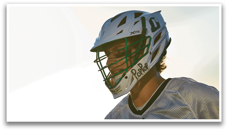 A man in a green shirt and white shorts is running with a lacrosse stick. Description generated by AI