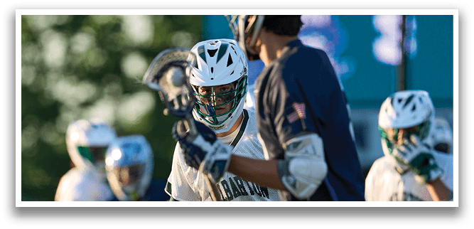 A man in a green shirt and white shorts is running with a lacrosse stick. Description generated by AI