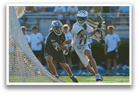 A man wearing a green and white uniform is holding a lacrosse stick. Description generated by AI