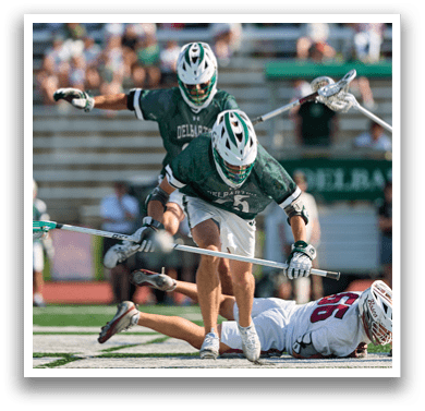 A man wearing a green and white jersey holding a lacrosse stick. Description generated by AI