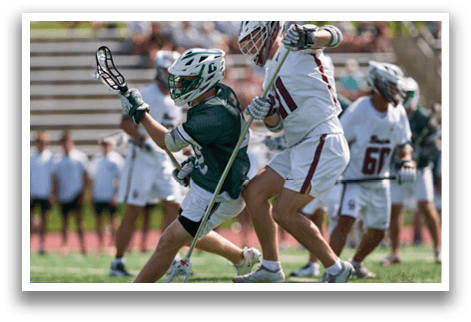 A man in a green and white uniform is running with a lacrosse stick. Description generated by AI