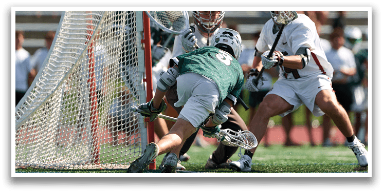 Two men playing lacrosse on a field. Description generated by AI