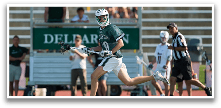 A group of men playing lacrosse. Description generated by AI