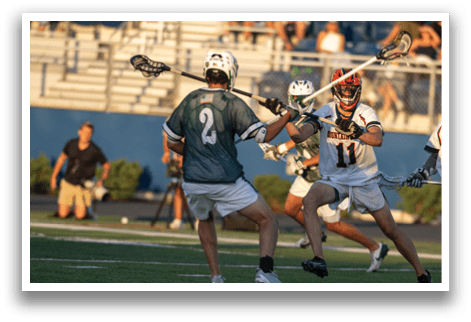 A man wearing a green and white uniform is holding a lacrosse stick. Description generated by AI