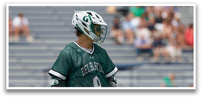 A man in a green shirt and white shorts is running with a lacrosse stick. Description generated by AI