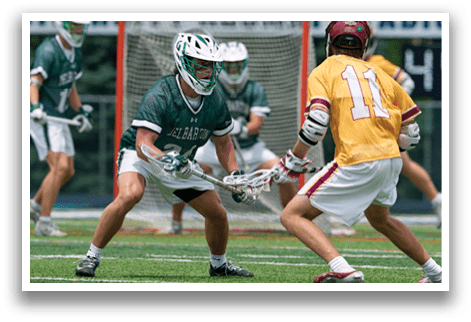 A man in a green and white uniform is running with a lacrosse stick. Description generated by AI