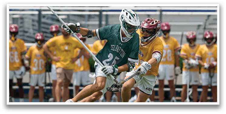 A man wearing a green and white shirt holding a lacrosse stick. Description generated by AI