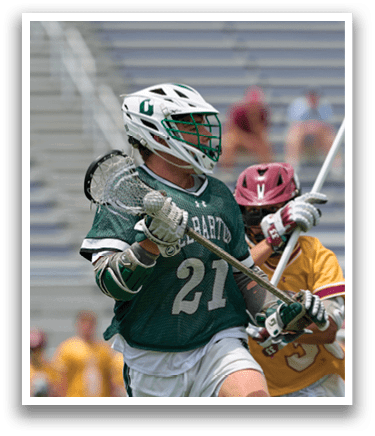 A man wearing a green shirt and white shorts is playing lacrosse. Description generated by AI