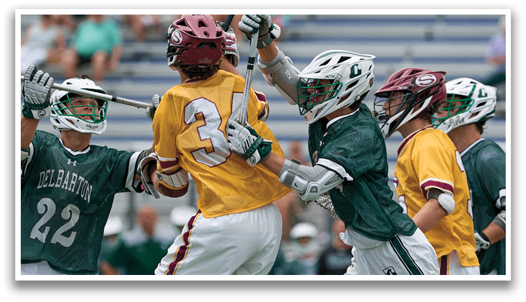 A man wearing a green shirt and white shorts holding a lacrosse stick. Description generated by AI