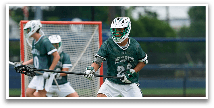 Two men playing lacrosse on a field. Description generated by AI