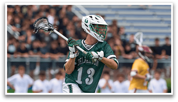 A man is sliding on the ground while another man is holding a lacrosse stick. Description generated by AI