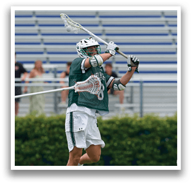 A man wearing a green and white jersey holding a lacrosse stick. Description generated by AI
