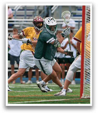 A man wearing a green and white uniform holding a lacrosse stick. Description generated by AI
