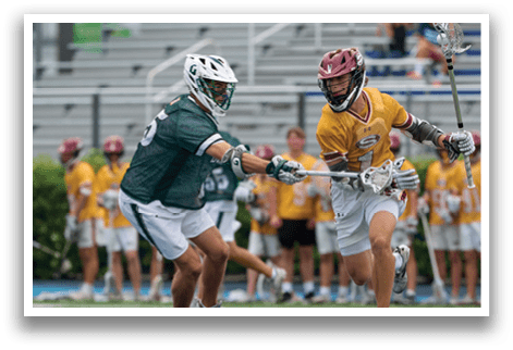 A man in a green shirt and white shorts is holding a lacrosse stick. Description generated by AI