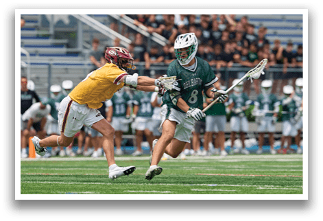 A man wearing a green and white uniform is holding a lacrosse stick. Description generated by AI