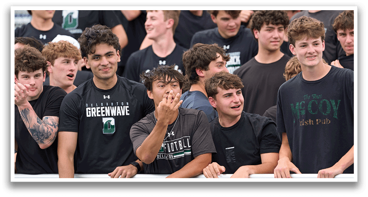 A group of young men in green and white uniforms pose for a picture. Description generated by AI