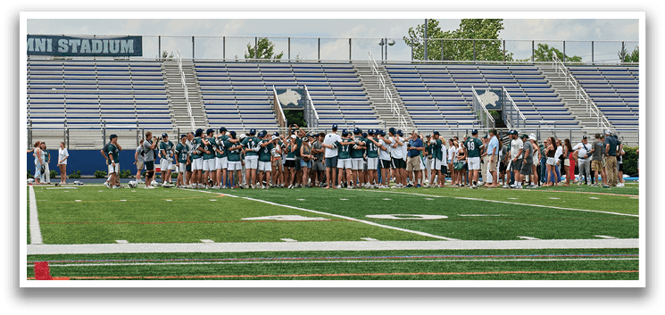 A group of young men wearing green and white uniforms. Description generated by AI