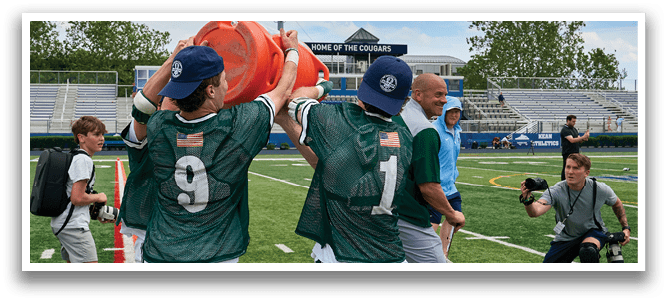 A group of people standing together, one of them wearing a jersey with the number 33. Description generated by AI
