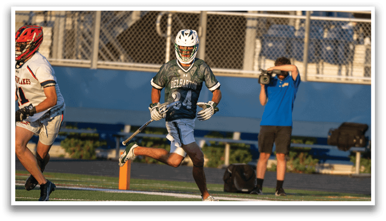 A man is sliding on the ground while another man is holding a lacrosse stick. Description generated by AI