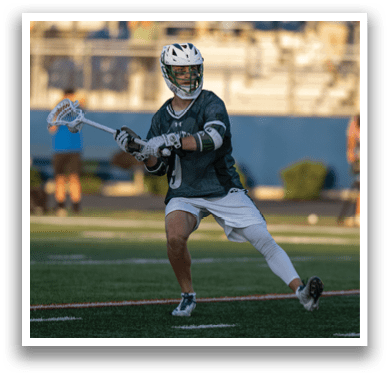 A man wearing a green and white jersey holding a lacrosse stick. Description generated by AI
