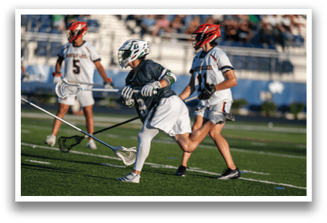 A man in a green and white uniform is running with a lacrosse stick. Description generated by AI