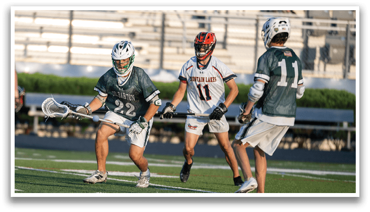 A man wearing a green shirt and white shorts holding a lacrosse stick. Description generated by AI