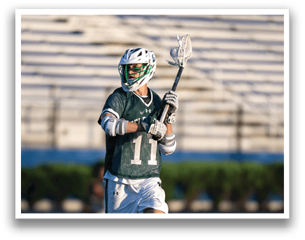 A person wearing a green and white shirt and holding a lacrosse net. Description generated by AI