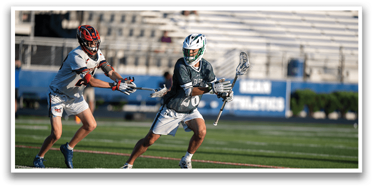 A man wearing a green and white shirt holding a lacrosse stick. Description generated by AI