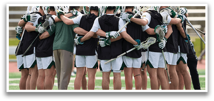 A group of lacrosse players huddled together on the field. Description generated by AI