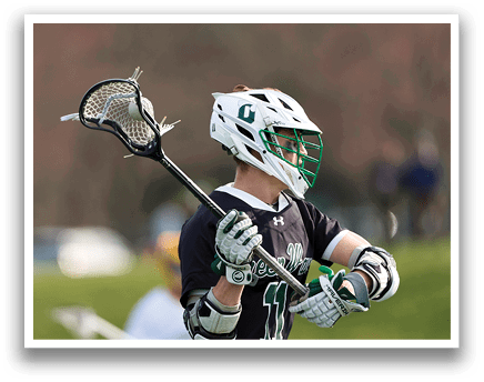 A man wearing a black shirt and holding a lacrosse stick. Description generated by AI