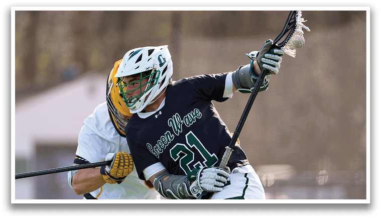A man wearing a black shirt and white pants is holding a lacrosse stick. Description generated by AI