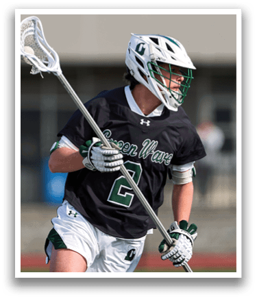 A man wearing a black shirt and white shorts holding a lacrosse stick. Description generated by AI