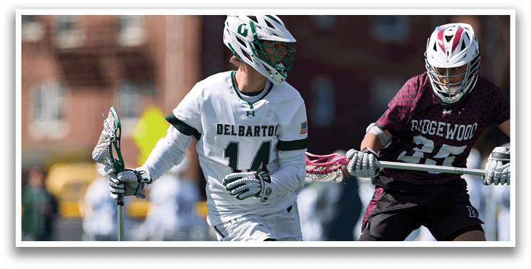 Two men playing lacrosse on a field. Description generated by AI